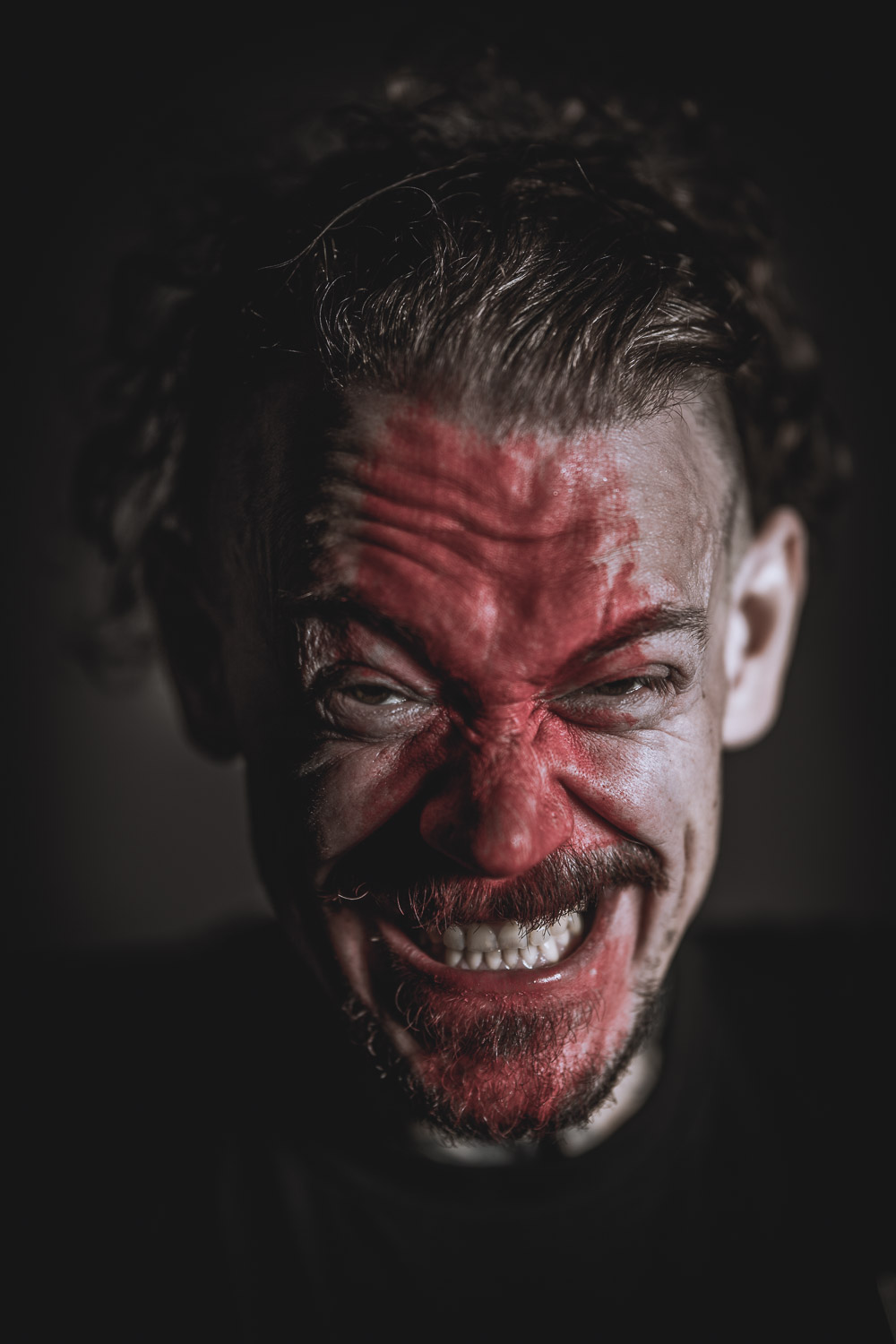 Ein Mann mit einem wütenden Gesicht, das rot bemalt ist.